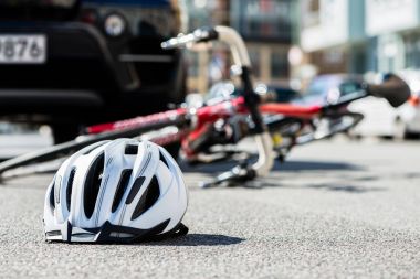 Close-up of a bicycling helmet on the asphalt  next to a bicycle clipart