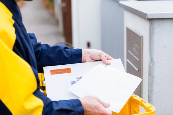 Postman delivering letters to mailbox of recipient
