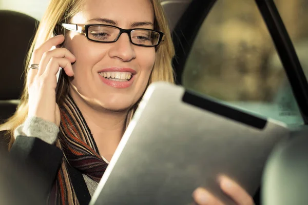 Junge Geschäftsfrau fährt im Taxi, sie nutzt einen Tablet-Computer — Stockfoto