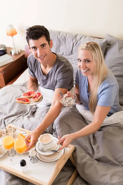 Ευτυχισμένο νεαρό ζευγάρι τρώει πρωινό στο κρεβάτι — Φωτογραφία Αρχείου