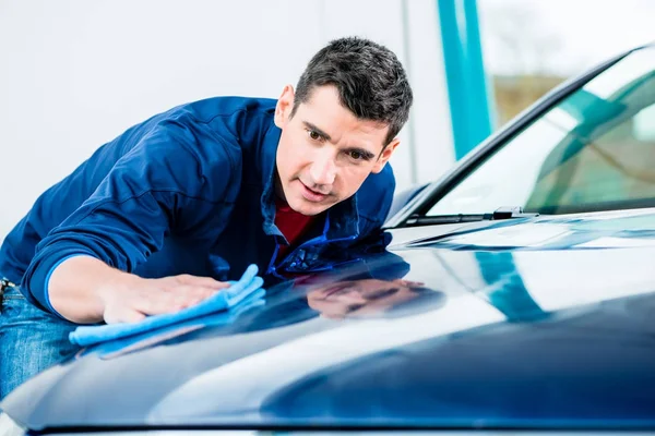 Uomo che utilizza un asciugamano assorbente per asciugare la superficie di un'auto — Foto Stock