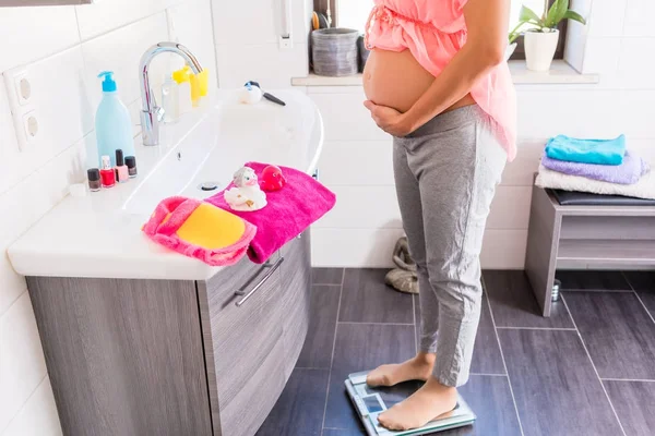 Mocno ciąży kobieta na skali w łazience — Zdjęcie stockowe
