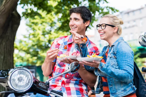 Pareja de turistas descansando durante el tour en scooter comiendo currywurst —  Fotos de Stock