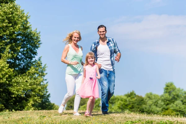 Father, mother, daughter running down a hill — Stock Photo, Image
