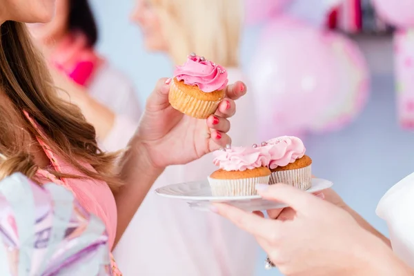 Expecting mother eating cupcake on baby shower party