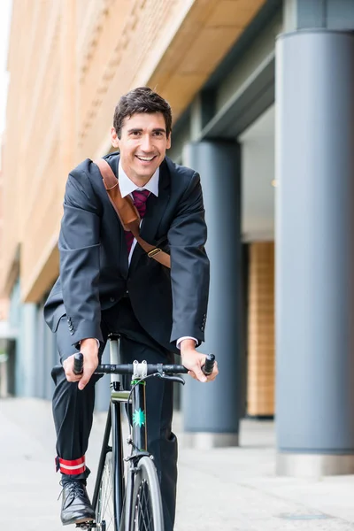 Jovem ativo sorrindo enquanto andava de bicicleta utilitária para sua wor — Fotografia de Stock