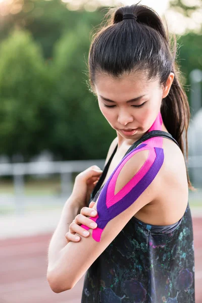 Woman taping with therapeutic tape on cinder track of sports sta — Stock Photo, Image