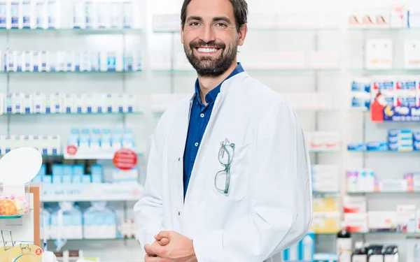 Boticario en farmacia de pie en el estante con medicamentos —  Fotos de Stock