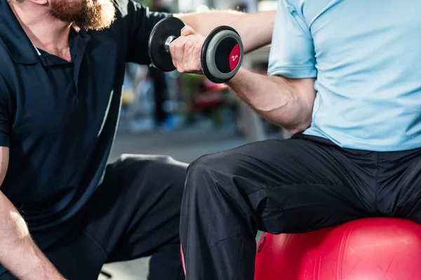 Seniorchef trainiert mit Personal Trainer im Fitnessstudio — Stockfoto