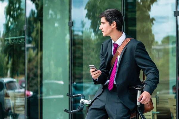 Joven empleado corporativo sosteniendo un teléfono móvil mientras espera ou — Foto de Stock