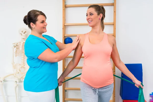 Mujer embarazada haciendo ejercicio con fisioterapeuta y resistanc —  Fotos de Stock