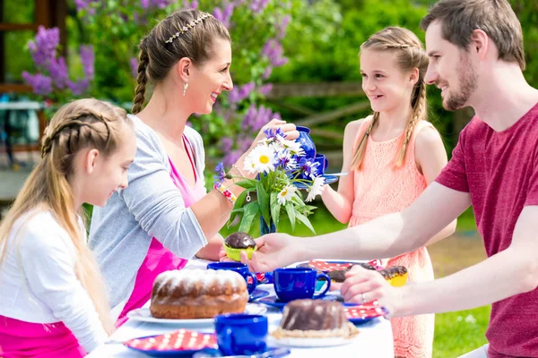 Familie som drikker kaffe i hagen, spiser kake – stockfoto