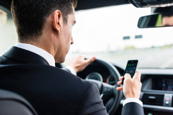 Man texting on his phone while driving car