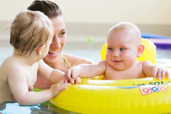 Madri e bambini si divertono insieme giocando con i giocattoli in piscina — Foto Stock