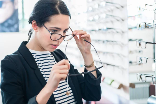 Vrouw vergelijkt bril bij opticien — Stockfoto