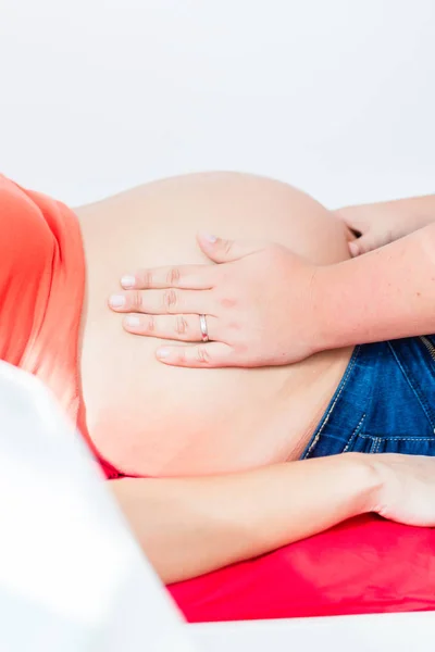 A Bába exanimating terhes nő hasa kézzel — Stock Fotó
