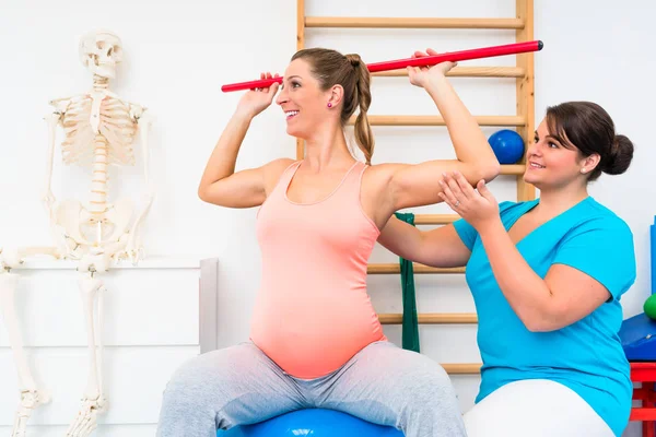 Gravid kvinna som tränar i sjukgymnastik med gymnastiska pinne — Stockfoto