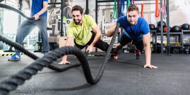 Men with battle rope in functional training fitness gym clipart