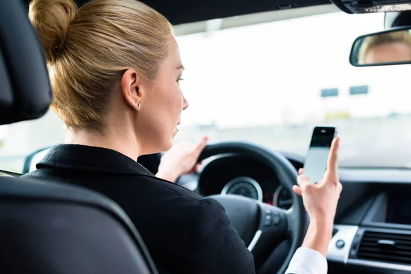 Perempuan SMS di ponselnya saat mengemudi dengan mobil — Stok Foto