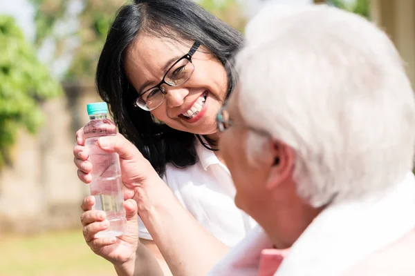 Zorgvuldige senior vrouw een fles water te geven aan haar partner uit — Stockfoto