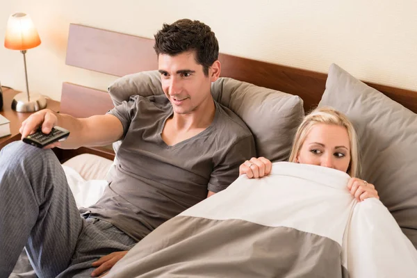 Casal sentado na cama enquanto assiste TV — Fotografia de Stock