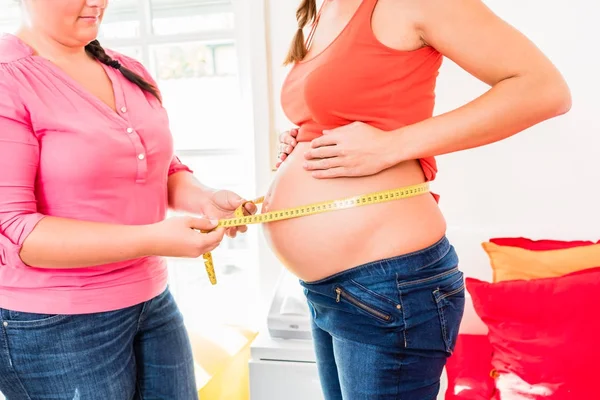 Mujeres embarazadas de pie y partera que miden la circunferencia de b —  Fotos de Stock
