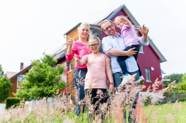 Anne, baba ve çocuk evin önünde