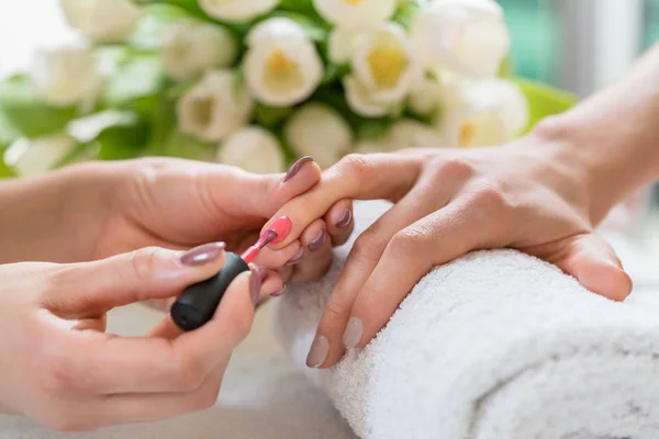 Manos de una manicura experta aplicando esmalte de uñas rojo en la na — Foto de Stock