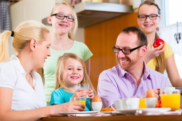 Familie hjemme som spiser frokost på kjøkkenet – stockfoto