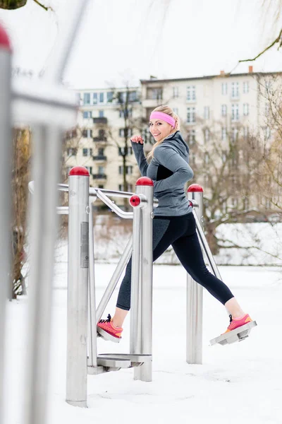Young woman training her legs on fitness path on winter day — Stock Photo, Image