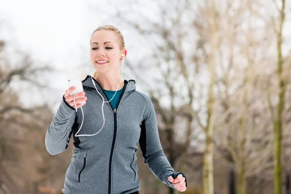 Mujer corriendo por un camino en el día de invierno en el parque —  Fotos de Stock