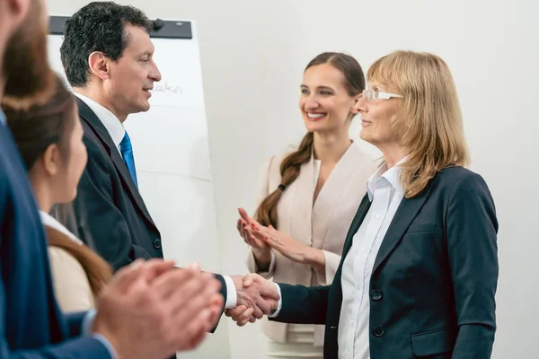 Two middle-aged business associates smiling while shaking hands — Stock Photo, Image
