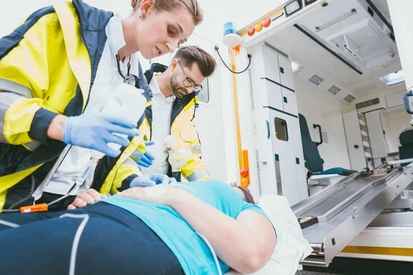 Läkare med infusionen och syre tar hand om kvinnan — Stockfoto