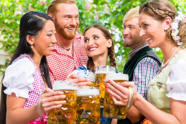 Gli amici si divertono nel giardino della birra mentre si tintinnano gli occhiali — Foto Stock