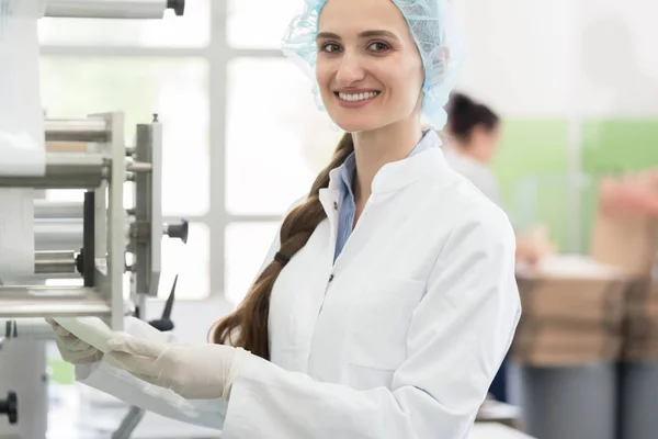 Šťastní zaměstnanci nosit plášť při zpracování sterilní tampóny v — Stock fotografie