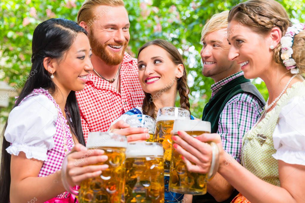 Friends having fun in beer garden while clinking glasses
