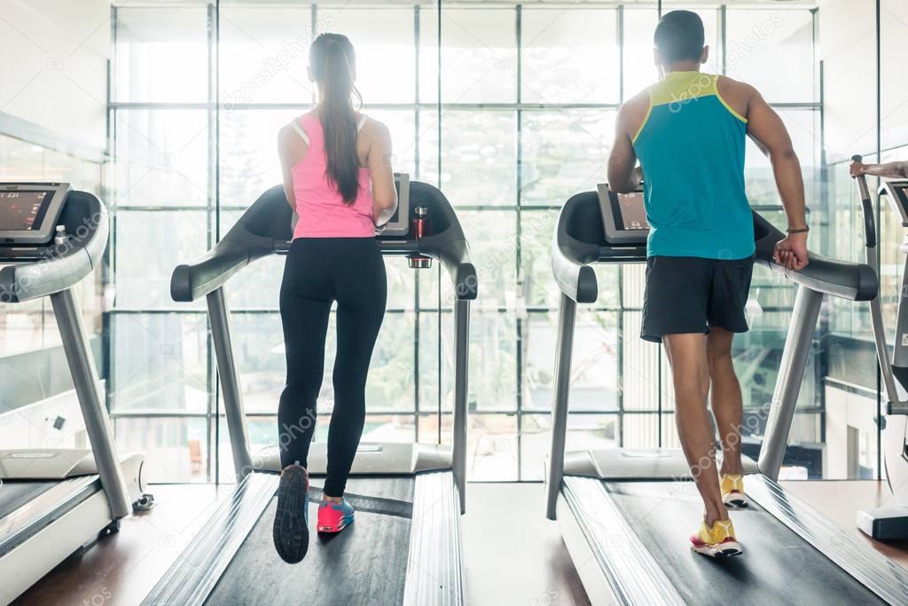 Rear view of a fit woman and her cardio workout partner running