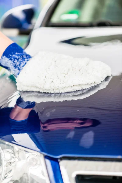 Hombre puliendo el capó de su coche de lujo — Foto de Stock