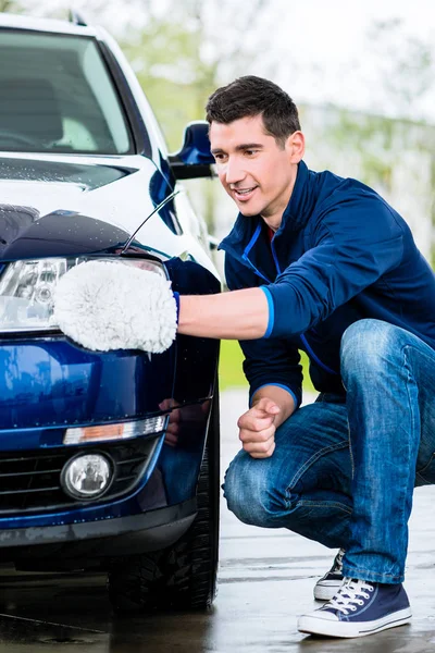 Proud car owner cleaning the headlamps — Stock Photo, Image
