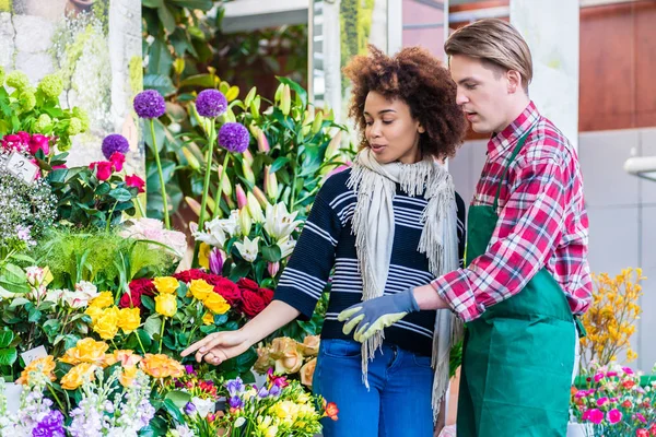 Beautiful woman buying freesias at the advice of a helpful vendo — Stock Photo, Image