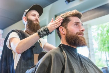 Yakışıklı genç adam modaya uygun bir saç kesimi için hazır bir serin sakallı.