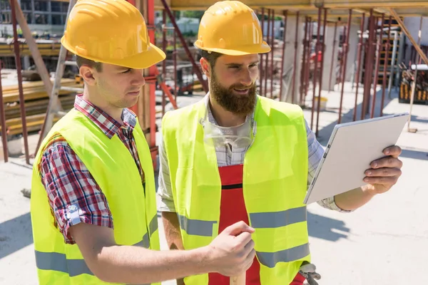 Zwei junge Arbeiter, die sich ein Video ansehen oder online kommunizieren — Stockfoto