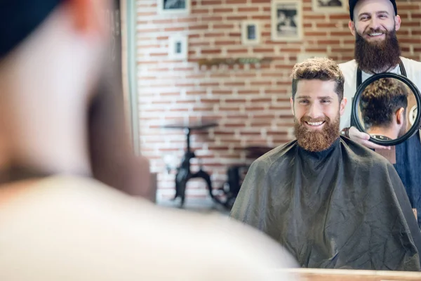 Jeune homme souriant en regardant sa nouvelle coupe de cheveux à la mode dans le — Photo