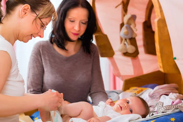 Hebamme untersucht Neugeborenes — Stockfoto