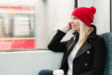 Kadın telefonu kullanarak tren pencereden dışarı bakıyor