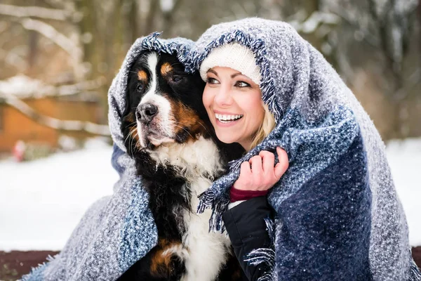 Vrouw en haar hond krijgen warm op koude winterdag onder een blanke — Stockfoto