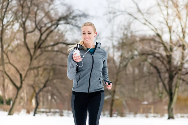 Mujer corriendo por un camino en el día de invierno en el parque —  Fotos de Stock