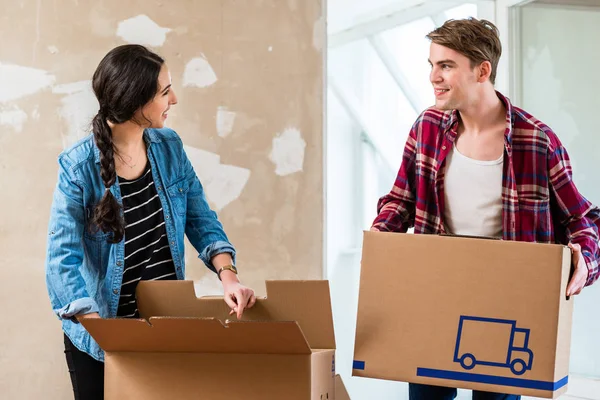 Joven hombre abriendo una caja mientras se mueve con su novia en un — Foto de Stock