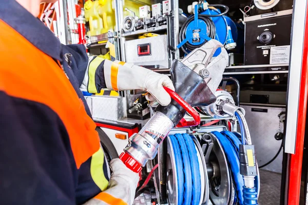 Fire fighter checking hydraulic cutter at fire engine — Stock Photo, Image