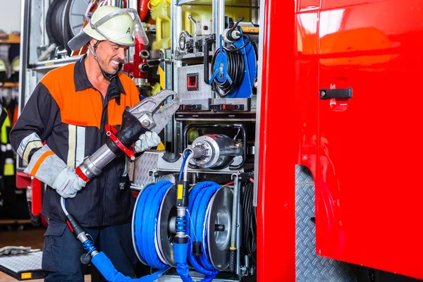 Fire fighter checking hydraulic cutter at fire engine — Stock Photo, Image